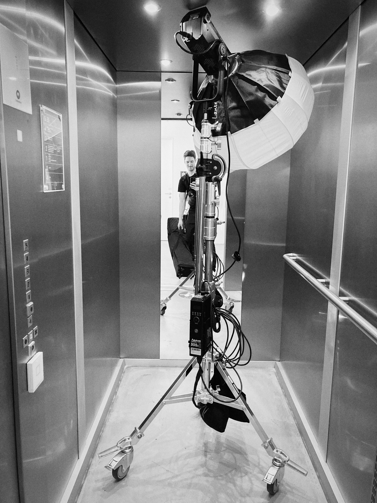 Eine Person steht mit einer großen Fotoleuchte auf Rädern in einem Aufzug und verkörpert den authentischen Stil eines Düsseldorfer Fotografen. Portrait und Reportage Fotografie für Corporate und Editorial