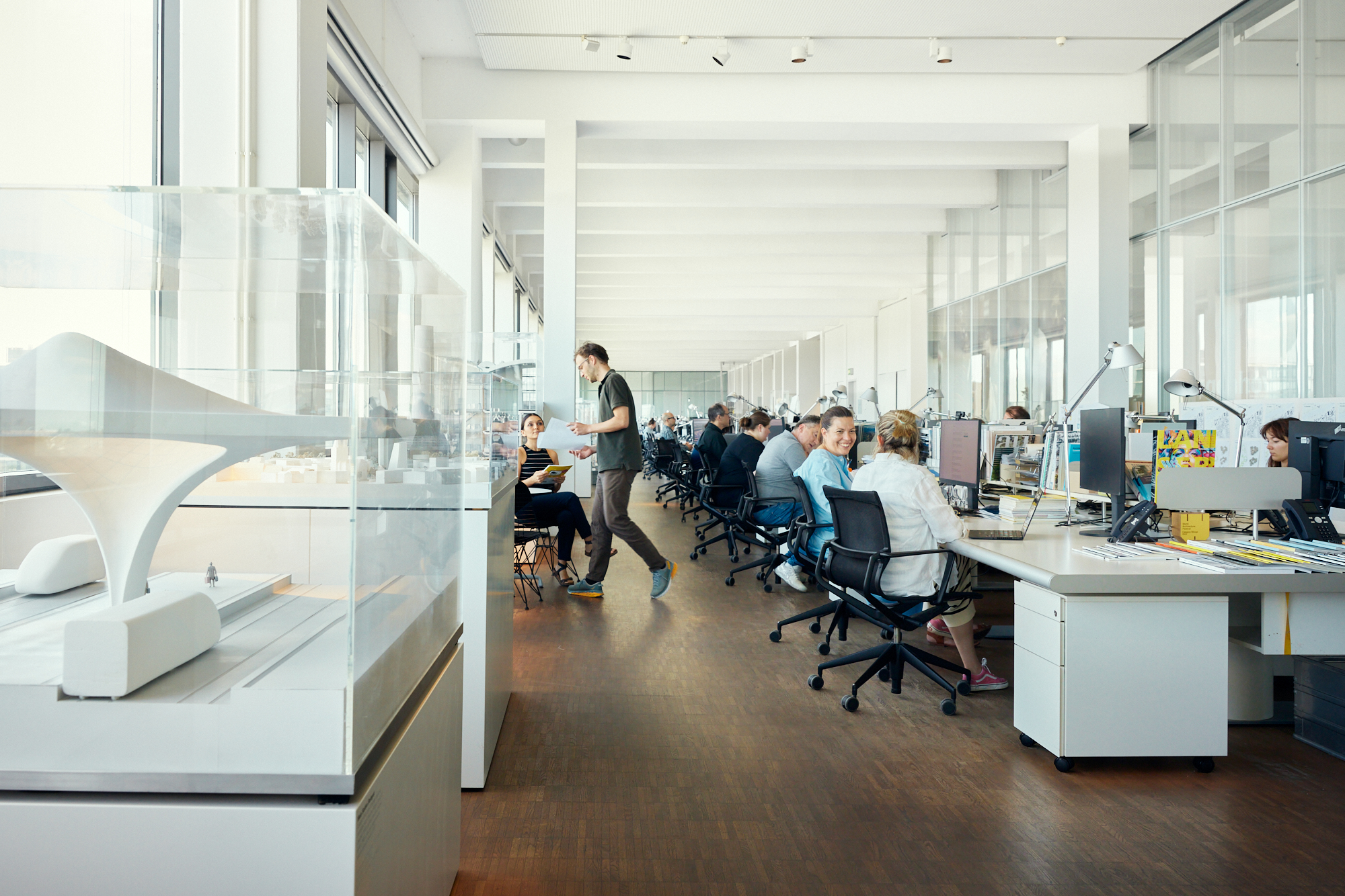 Großzügiges, modernes Büro in Düsseldorf mit Büros für professionelle Mitarbeiter. Ein Architekturmodell ist prominent am Eingang ausgestellt und verkörpert die Essenz des Unternehmensalltags. Große Fenster durchfluten den Raum mit natürlichem Licht und machen ihn ideal für Unternehmensfotografie. Portrait und Reportage Fotografie für Corporate und Editorial